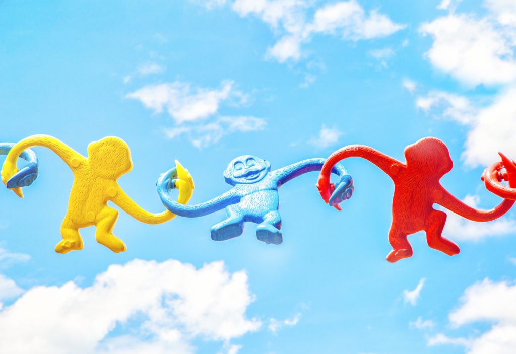 picture of toy monkeys in a chain of support with the background of a blue sky