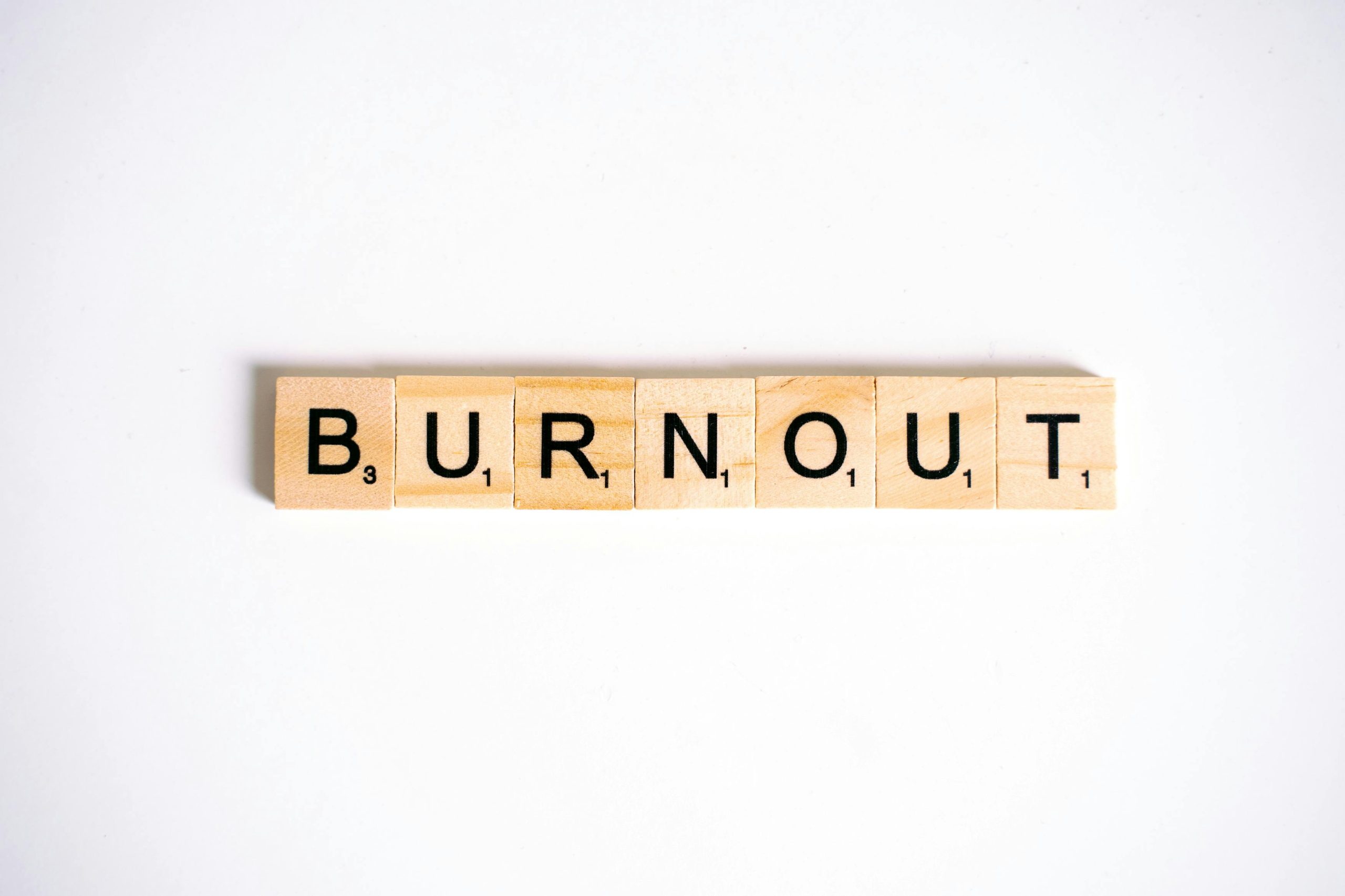 White background, wooden letter scrabble tiles spelling the word BURNOUT