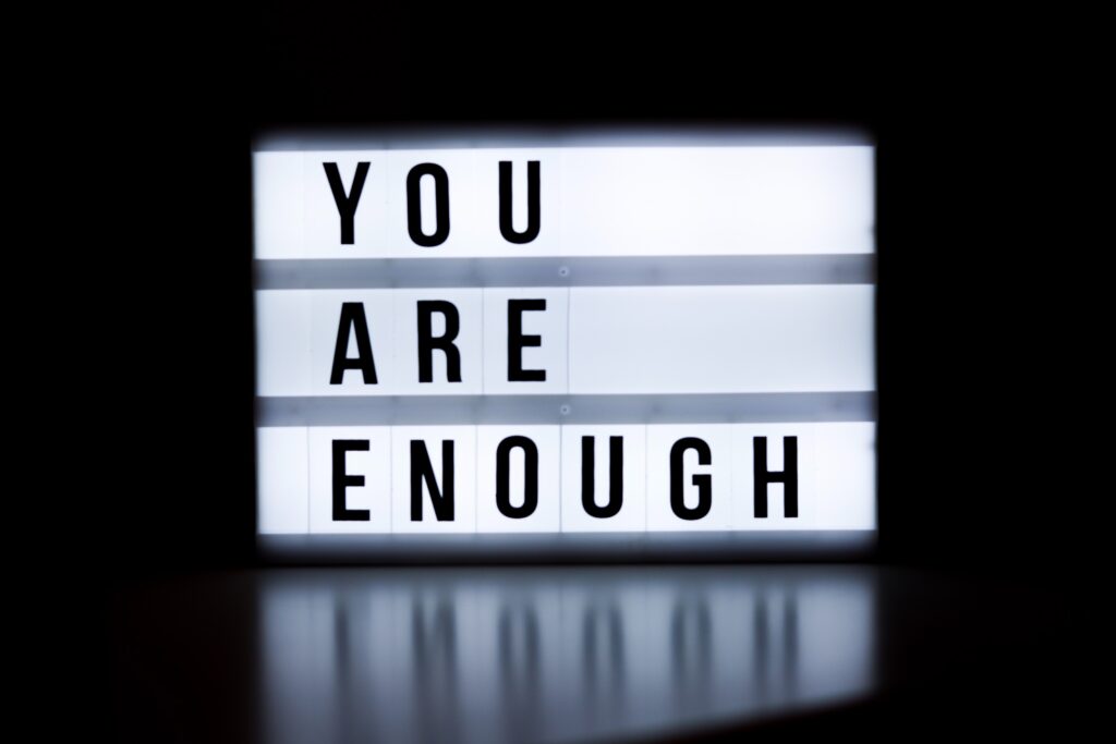 Dark background and a white lightbox with black letters that say 'You are enough'