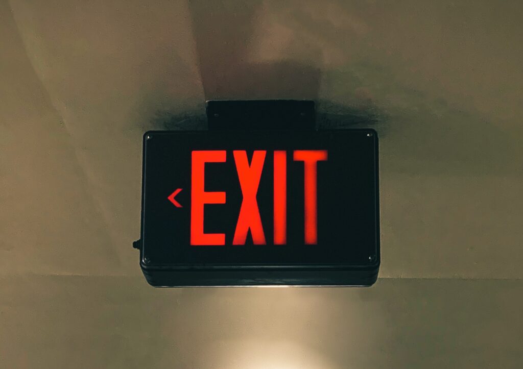 Black box mounted to a wall with a red exit sign inside