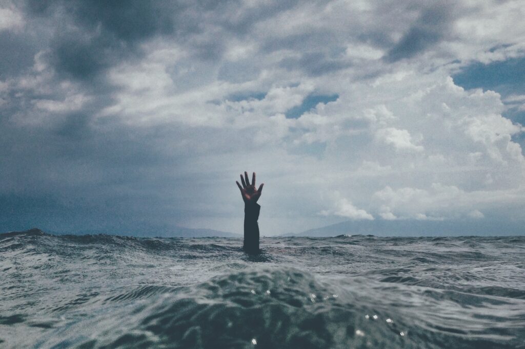 Hand outstretched from the waves in the sea, as if crying out for help