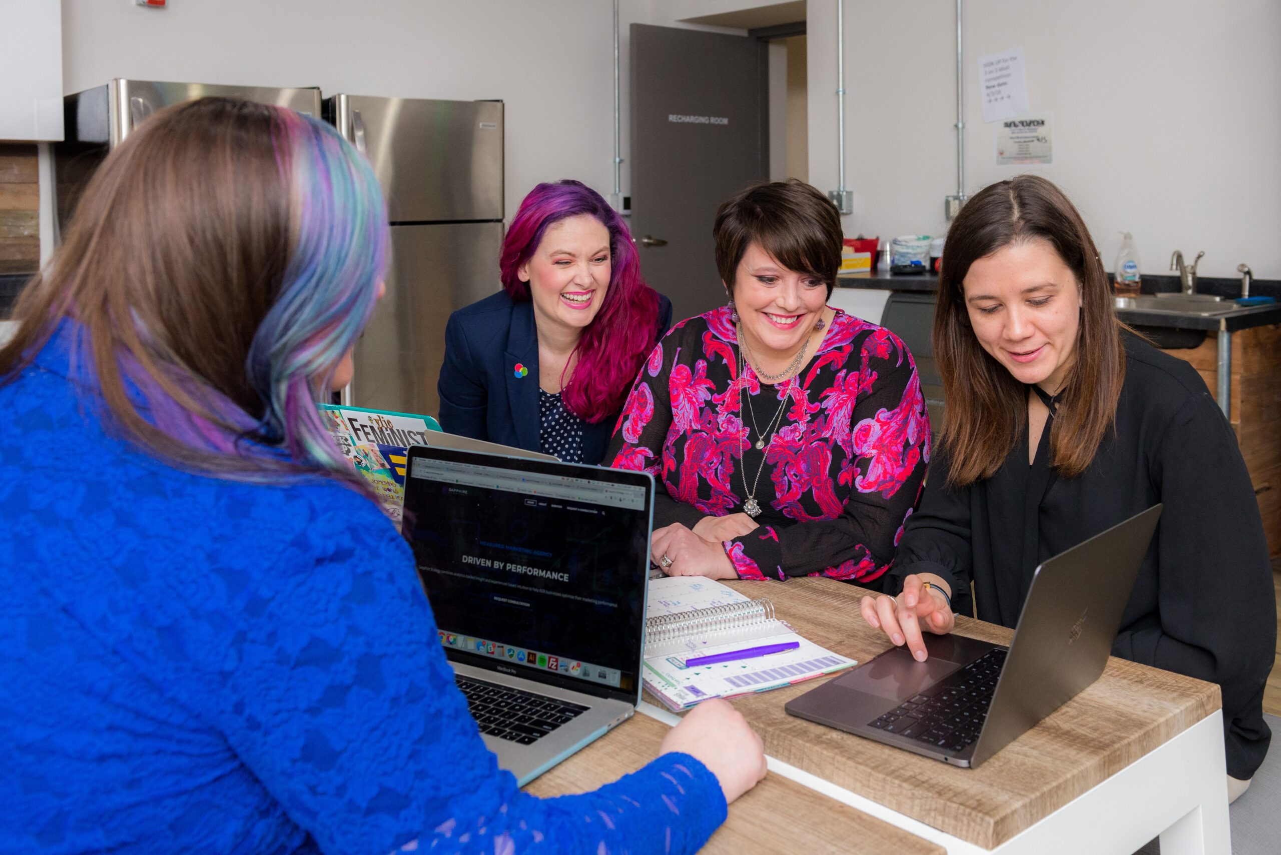 a group of women who are sitting at the same table are working on a project together with one woman leading them through content on a laptop screen